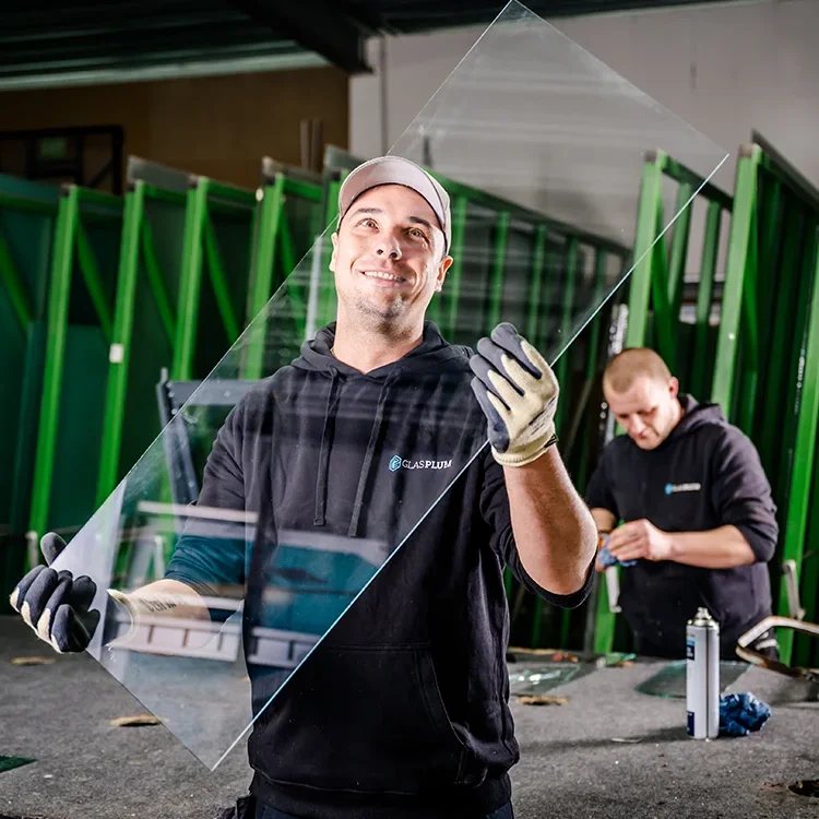 Junger, zufriedener Glaser Jülich von Glas Plum kontrolliert die Qualität einer Glasscheibe.