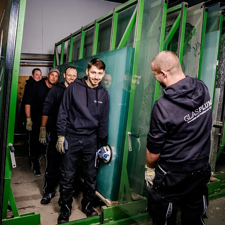 Teamwork bei Glas Plum aus Jülich beim gemeinsamen Tragen einer Glasscheibe.